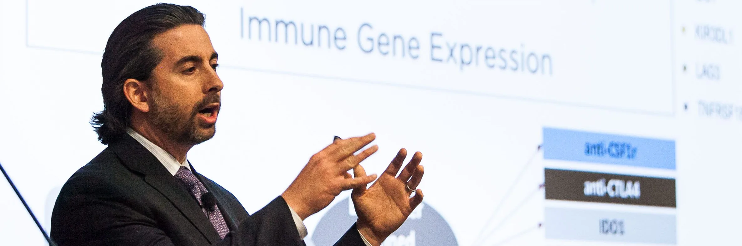 photo of a man in business atire on a stage talking to an audience